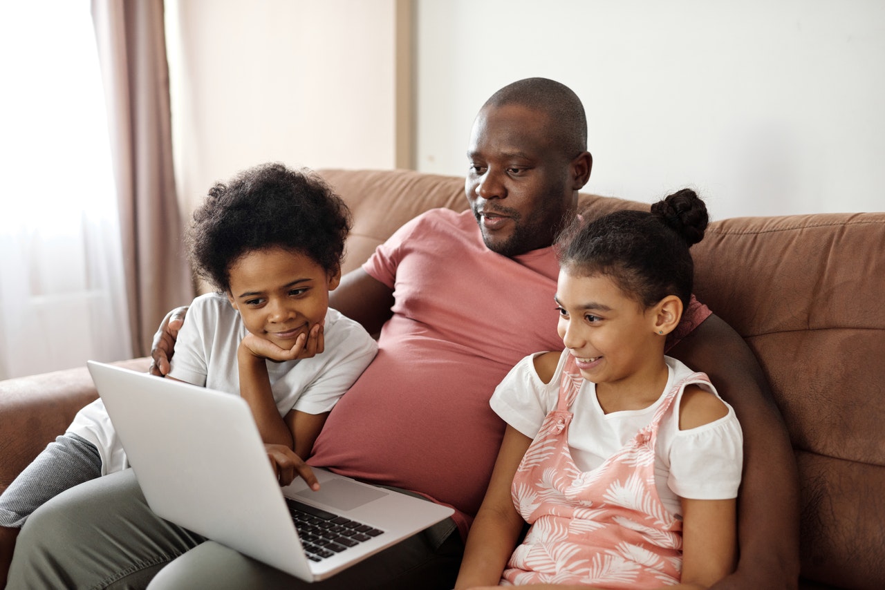father and children watching a video on their computer