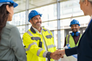 Smiling engineer shaking the hands of a businesswoman at a construction site.